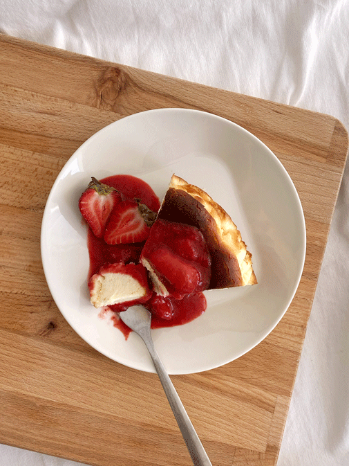 A slice of Basque Burnt Cheesecake topped with strawberry compote